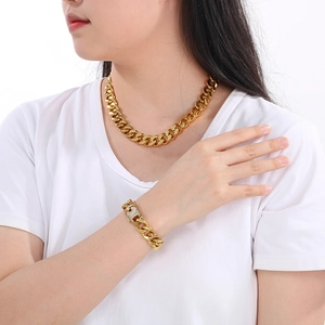 Detail of gold Cuban link chain set with sparkling CNC stones on the clasp worn by model