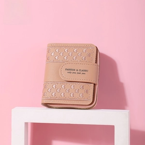 Detail of pink PU leather wallet with heart embroidery and golden zipper closure
