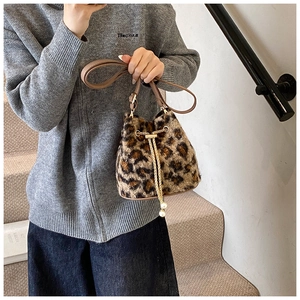 Detail of leopard print plush bucket bag with gold chain strap and pearl charm accent