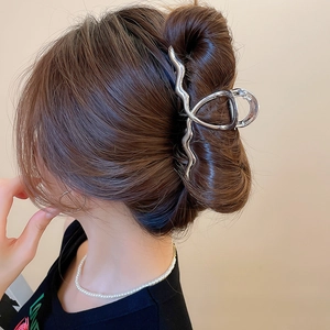 Close-up of silver wavy metal hair claw clip with liquid metal texture on model hair