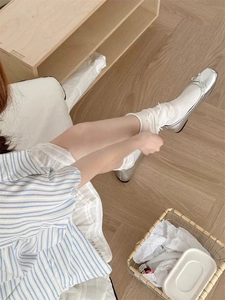 Vista dall'alto di ballerine argento con fiocco delicato su pavimento in legno