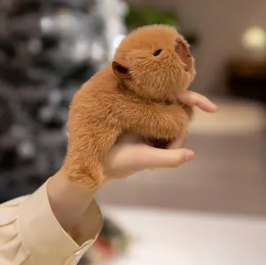 Close-up of fluffy brown capybara plush magnet being held in hand with soft bokeh