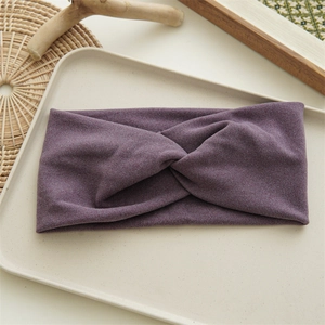 Détail d'un bandeau torsadé en tissu violet pour femme sur fond beige minimaliste