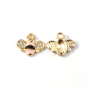 Dettaglio fronte e retro di un ciondolo ad ape dorato con smalto rosa e strass