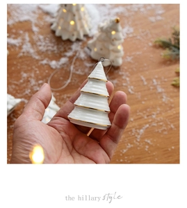 Close-up of a white ceramic mini Christmas tree ornament with elegant gold trim detail