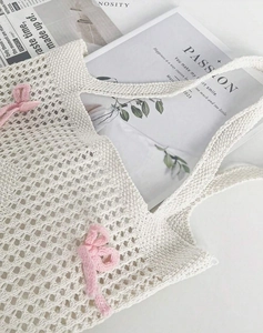 Detail of hollow knit tote bag in cream with a cute pink bow and woven texture