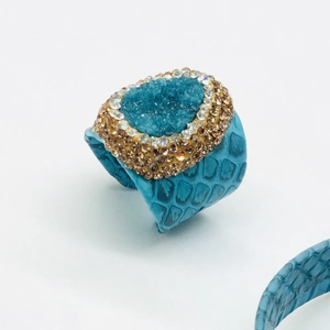 Détail de la bague en cuir de serpent bleu avec amas de cristaux et strass brillants