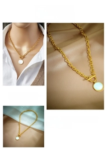 Detail view of gold chunky chain necklace featuring an OT toggle clasp and white shell pendant