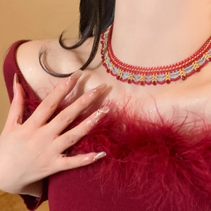 Close-up of handmade red braided choker with gold and silver beads in ethnic style