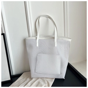 Detail of white mesh beach tote bag featuring matching smooth handles on black surface