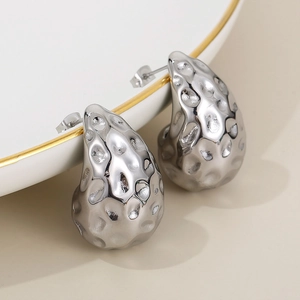 Macro view of silver teardrop hollow earrings with unique hammered texture and metal finish