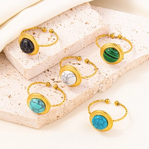 Detail of five adjustable gold rings with marbled gemstones on a natural stone surface