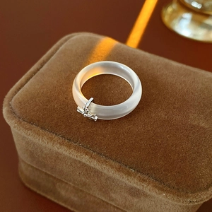 Close-up of translucent chalcedony ring with silver dragonfly charm on brown velvet box