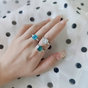 Detailed shot of three rectangular emerald cut moissanite rings in blue, white, and green