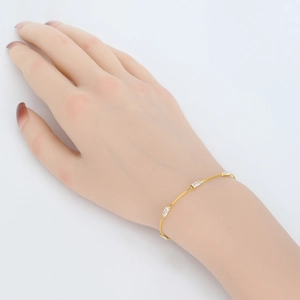 Detailed macro view of an elegant gold bracelet featuring four rectangular clear crystals