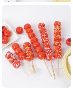 Detalle de brochetas de frutas confitadas artificiales con brillo sobre bandeja blanca
