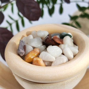 Macro shot of assorted smooth aromatherapy crystal stones in a round vertical wooden bowl