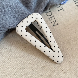 Dettaglio macro della molletta a triangolo in tessuto con pois bianchi e neri