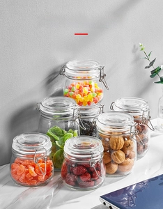 Airtight glass jars with metal buckles containing dried fruits and nuts on marble counter