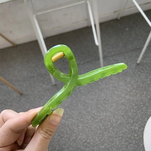 Detail of a bright green large claw clip showing the durable golden metal spring mechanism