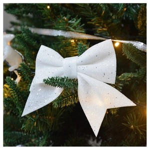 Sparkly white Christmas bow ornament with silver glitter on festive pine tree branches