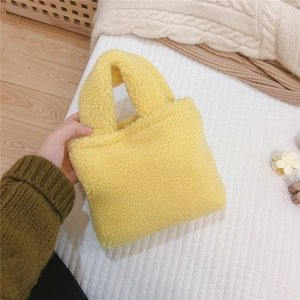 Gros plan sur la texture du mini sac à main en laine d'agneau jaune et ses anses