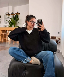 Close-up of a cozy black V-neck sweater paired with denim jeans in a modern room setting
