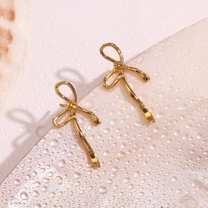 Detailed view of an 18K gold-plated ribbon bow earring on a water droplet background