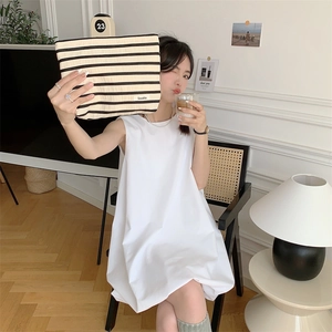 Modern scene of a striped canvas cosmetic bag held by a model in a minimalist home setting