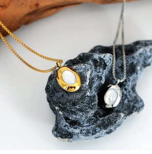 Detailed shot of oval shell pendants in gold and silver hanging on stone textures