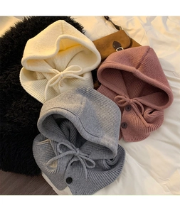 Detail of knitted balaclava beanies with drawstring and buttons in cream, gray, and pink