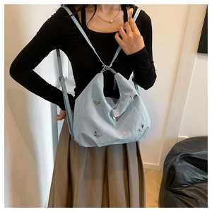 Detail of light blue versatile backpack featuring pleated fabric and metal butterfly clasp