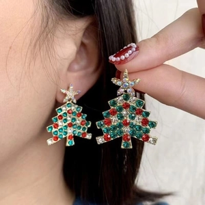 Close-up of gold Christmas tree earrings with colorful rhinestones on a female model