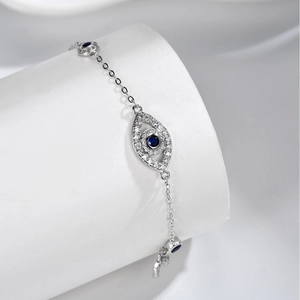 Minimalist S925 sterling silver evil eye bracelet with blue gemstone on a white pedestal