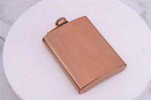 Top view of rose gold stainless steel hip flask with screw cap on marble plate