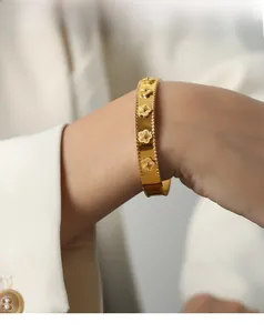 Macro detail of gold floral bangle featuring beaded Perlée edges and polished finish