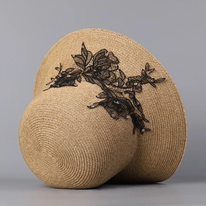 Detailed shot of straw sun hat featuring elegant black floral lace and bead embroidery