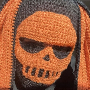 Macro shot of handmade crochet skull balaclava with orange skeletal knit details