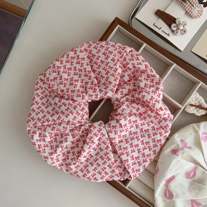 Detail of red bow print cotton scrunchie on a wooden display for a sweet aesthetic style