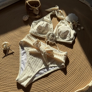 Detailed view of cream textured bikini fabric with shell decor on beach mat