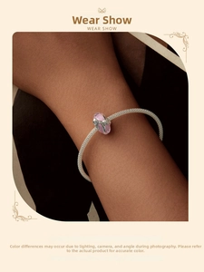 Détail d'un bracelet en maille argentée avec une perle en verre rose et nœud délicat
