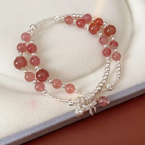 Dettaglio del bracciale in quarzo fragola con ciondoli a campana e fiocco d'argento