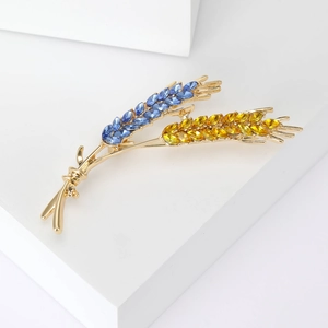 Detail of elegant gold wheat brooch featuring blue and yellow marquise-cut crystals