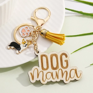 Detail view of Dog Mama keychain with yellow tassel and Corgi enamel charms on a plate