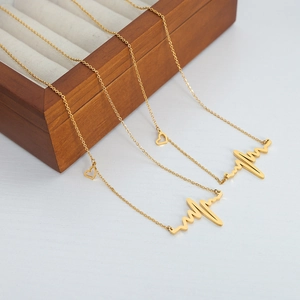 Titanium steel heartbeat necklace with gold heart pendant on a wooden jewelry display