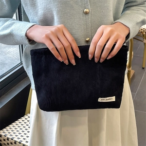 Detail of black corduroy makeup bag featuring a May Rabbit woven label on textured fabric