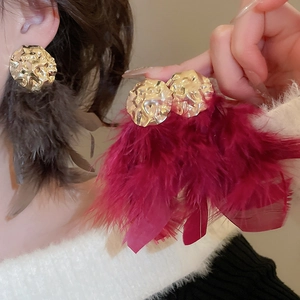 Detailed shot of golden hammered metal earrings with elegant grey and burgundy feathers