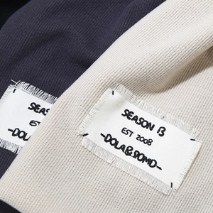Macro detail of knit fabric texture with vintage frayed patch and Season 13 embroidery