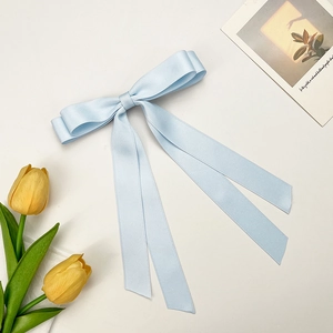 Detail of light blue satin double bow hair clip with long ribbons on white background