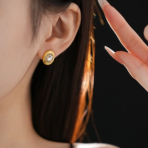 Close-up of vintage oval gold stud earrings with crystal inlay on a model's ear